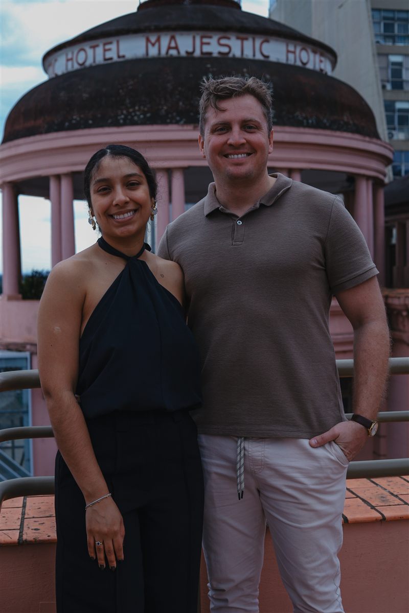 Casal sorrindo lado a lado diante de uma cúpula histórica